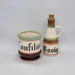 May include: A set of two vintage ceramic kitchen canisters with brown, green, and white stripes. The larger canister is labeled "Konfitüre" and the smaller one is labeled "Essig".