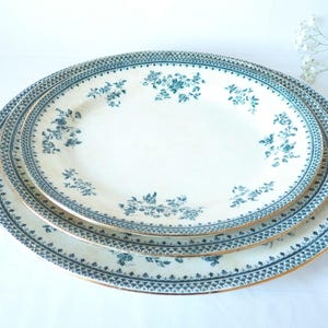 Puede incluir: Tres platos de cerámica blanca con un patrón floral azul y dorado. Los platos están apilados uno encima del otro.