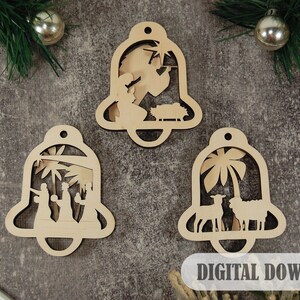 May include: Three wooden Christmas baubles shaped like bells with intricate cutouts depicting scenes from the Nativity story. The baubles are unfinished and ready to be painted or decorated.