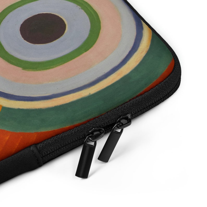 Pu&ograve; includere: Una custodia per laptop nera con chiusura a zip. La custodia presenta un design astratto colorato con cerchi concentrici in tonalit&agrave; di arancione, giallo, verde, blu e rosa.