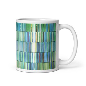 May include: White ceramic mug with a vibrant vertical stripe pattern in blues, greens, and yellows. The mug has a classic handle and a glossy finish, ideal for tea or coffee. The design is reminiscent of a barcode.
