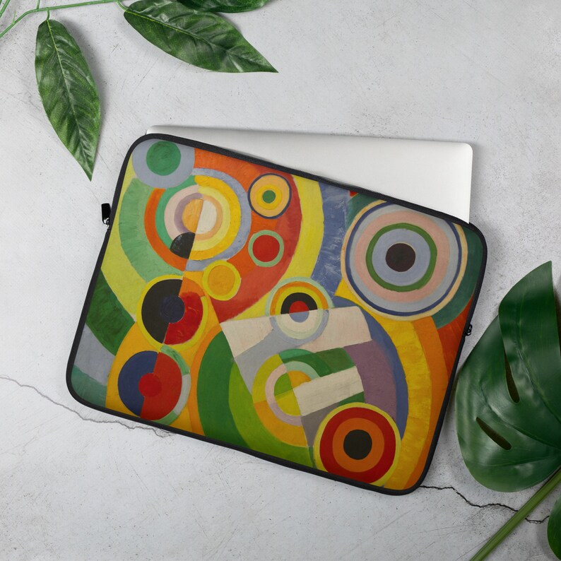 Pu&ograve; includere: Una custodia per laptop con un design geometrico astratto con cerchi e archi colorati. Il design ricorda un dipinto di arte moderna con una tavolozza di colori vibrante.