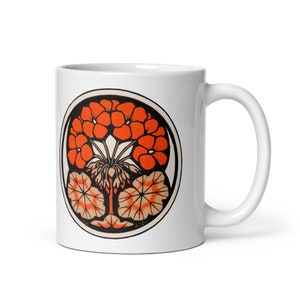 Pode incluir: Caneca de cerâmica branca com um design circular que apresenta um padrão floral estilizado em laranja e marrom. O design está centralizado na caneca e tem um contorno preto.
