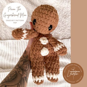 Könnte beinhalten: Häkelanleitung für ein Amigurumi-Spielzeug in Form eines Lebkuchenmanns namens "Pecan The Gingerbread Man". Das Muster ist als PDF-Download erhältlich. Das Bild zeigt einen braunen gehäkelten Lebkuchenmann mit weißen Details.