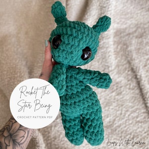 May include: A green crocheted alien toy with large black eyes. The toy is named "Rocket the Star Being" and is a crochet pattern PDF.