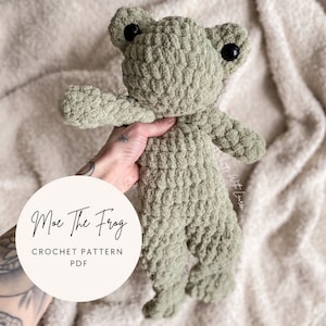 Może przedstawiać: Wzór na szydełku na zieloną zabawkę amigurumi w kształcie żaby. Wzór nazywa się "Moe the Frog" i jest dostępny do pobrania w formacie PDF.