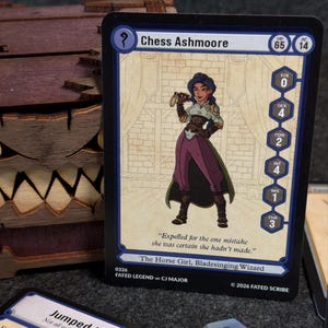 May include: A trading card featuring an illustration of a character named Chess Ashmoore. The card has a blue border and includes text such as "The Horse Girl, Bladesinging Wizard" and "Expelled for the one mistake she was certain she hadn't made."