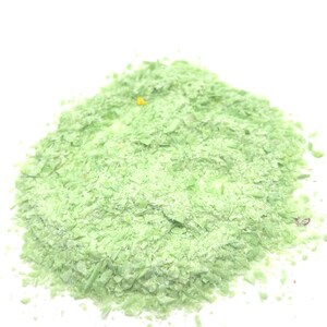May include: A pile of light green, finely ground, dried herbs. The herbs are in a loose, granular form, and appear to be a blend of different herbs.