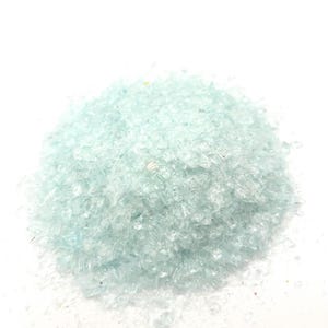 May include: A pile of light blue crushed glass, also known as glass glitter, on a white background.