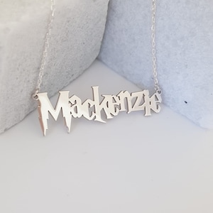 Puede incluir: Collar de plata con el nombre Mackenzie escrito en fuente g&oacute;tica.