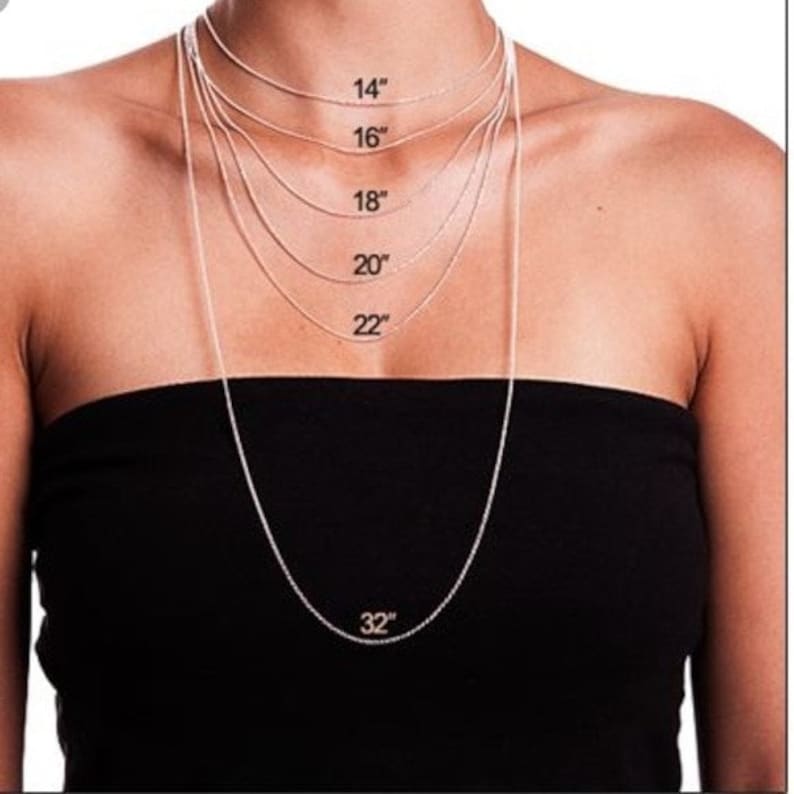 Puede incluir: Una modelo lleva una blusa negra con un collar de cadena plateada. El collar se muestra en diferentes longitudes, de 14 pulgadas a 32 pulgadas.