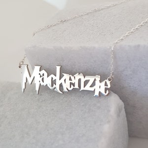 Puede incluir: Collar de plata con el nombre "Mackenzie" escrito en una fuente estilizada.