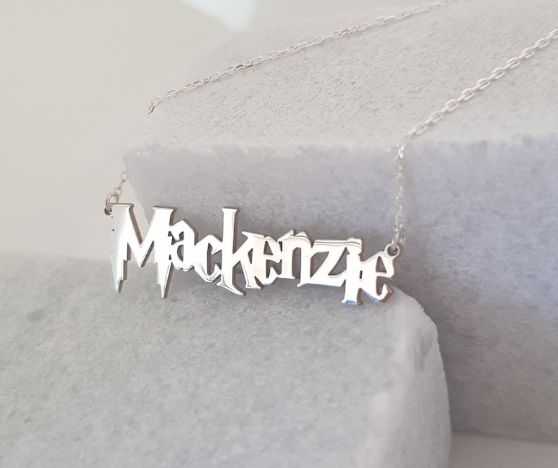 Puede incluir: Collar de plata con el nombre "Mackenzie" escrito en una fuente estilizada.