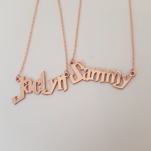 Puede incluir: Dos collares de oro con los nombres "Jaclyn" y "Sammy" escritos en letra g&oacute;tica.