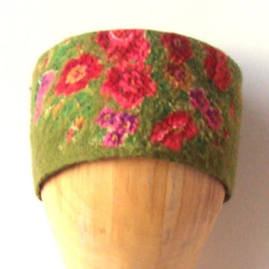 May include: A green felt headband with a floral print featuring pink, red, and purple flowers.