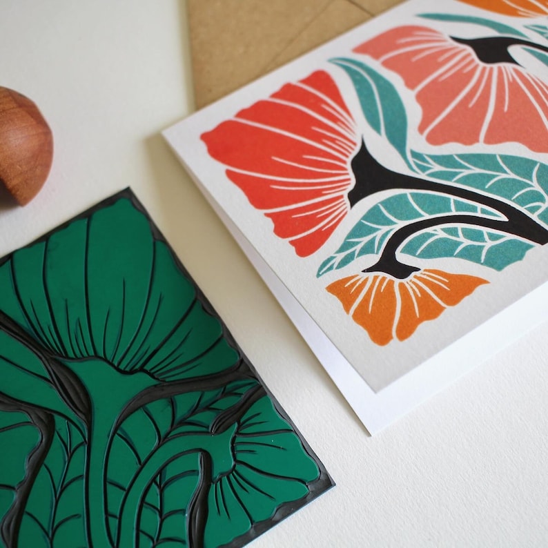 May include: Two cards with floral designs. One card features a green floral pattern with black outlines. The other card features a red, orange, and teal floral pattern with black outlines.