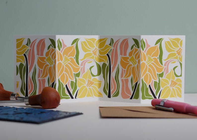 Daffodil botanical Garland card shown fully extended (105 x 297mm), displaying complete hand-carved linocut design. Modern cottagecore daffodil  portrait in pink, green and yellow, perfect for mantlepiece display.