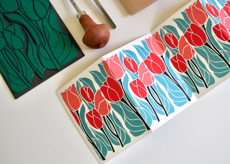 red and pink linocut tulips in a repeating pattern printed on to a folded concertina card