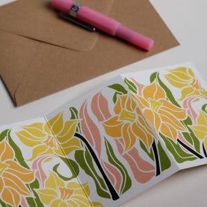 Daffodil Garland card with C6 kraft envelope. Hand-carved botanical portrait greeting card in yellow and pink on recycled cardstock, photographed with eco-friendly envelope, ready for posting.