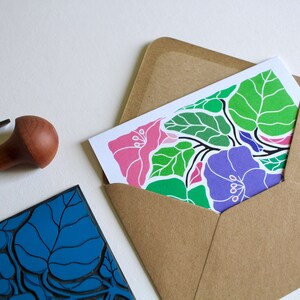 May include: A handmade greeting card with a floral design featuring pink, purple, and green flowers and leaves. The card is in a brown envelope.