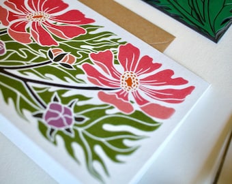 May include: A white card with a floral design featuring pink flowers and green leaves. The flowers are stylized and have a bold, graphic look.