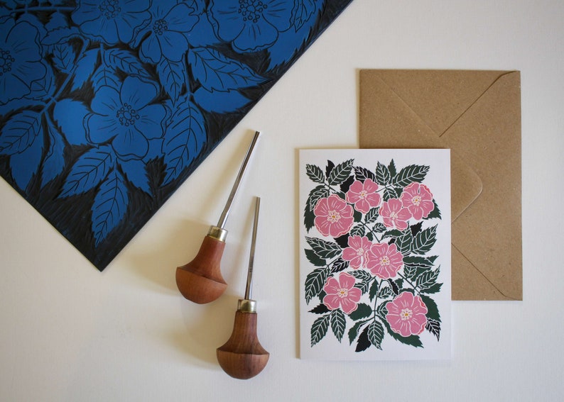 May include: A set of two wood handled carving tools with a card featuring a pink floral print. The card has a brown envelope.