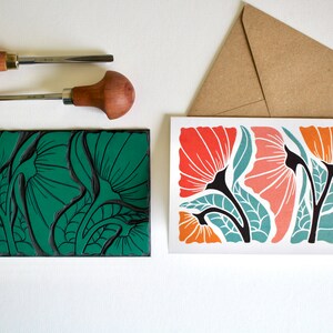 May include: A green linoleum block print of stylized flowers with a card showing the printed image in orange, red, and teal colors.