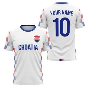 May include: White Croatia soccer jersey with blue accents and the word "CROATIA" in blue. The jersey has a Croatian coat of arms on the chest and the number 10 on the back. The sleeves have a red, white, and blue checkered pattern.
