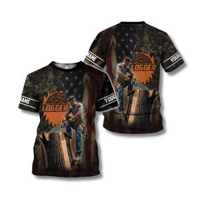 Op de afbeelding: Een T-shirt met korte mouwen met een houthakker die een kettingzaag gebruikt op een boomstronk. Het ontwerp bevat een Amerikaanse vlag en een camouflagepatroon. Het woord "LOGGER" wordt weergegeven, met ruimte voor een aangepaste naam op de mouwen.