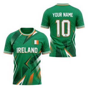 May include: Green Ireland soccer jersey with white and orange accents. The front features the word "IRELAND", the Irish flag, and a shamrock. The back displays the number 10 and space for a name. The jersey has a crew neck and short sleeves.