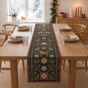 Pode incluir: Um caminho de mesa de tecido verde-escuro com um padrão repetitivo de cavalos Dala vermelhos, flocos de neve brancos, renas, corações, flores de poinsétia e pequenos pássaros. O caminho tem uma borda vermelha fina sobre uma mesa de madeira.