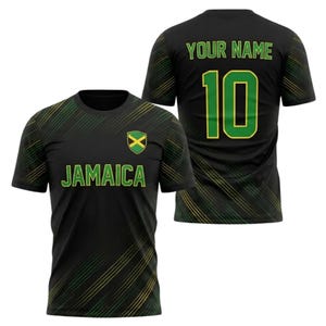 May include: Black t-shirt with green and yellow diagonal stripes. The front displays "JAMAICA" in green, a Jamaican flag emblem, and the back shows "YOUR NAME" above the number "10" in green with a yellow outline. A sporty design.