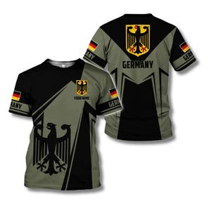 May include: A short-sleeved t-shirt featuring the German flag colors and emblem. The shirt has a black and olive green design with the German eagle and the word "GERMANY" printed on the back. The text "YOUR NAME" is also visible.