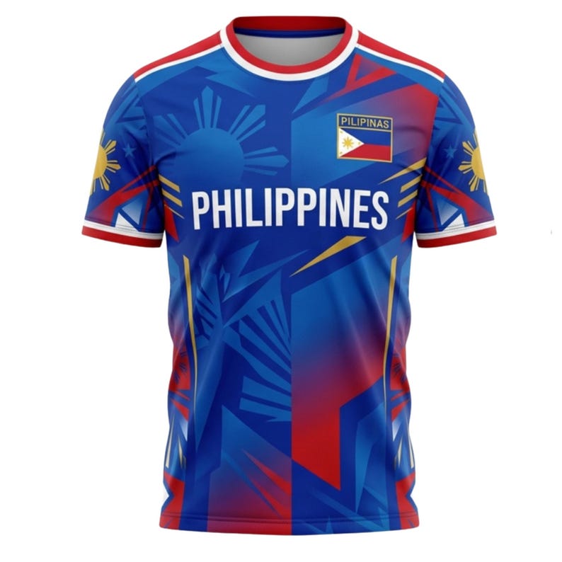 May include: Blue t-shirt with the word "PHILIPPINES" in white block letters. The shirt features a sun and star design, the Philippine flag, and the word "PILIPINAS". Red and yellow accents are on the sleeves and shoulders.