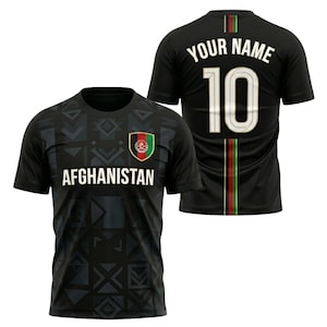 May include: Black soccer jersey with the word "AFGHANISTAN" across the chest and the Afghanistan flag emblem. The back of the jersey has the number 10 and the words "YOUR NAME". The jersey has a geometric pattern.