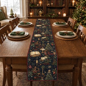 May include: A dark blue quilted table runner featuring a repeating pattern of Christmas trees, stacks of books, owls, keys, and snowflakes. The runner is centered on a wooden dining table with place settings including white plates and green napkins.