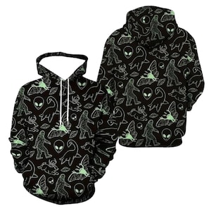 May include: A black hoodie featuring an all-over print of white and pale green line art illustrations. The pattern includes figures of Bigfoot, aliens, the Loch Ness monster, jackalopes, moths, and flying saucers across the front and back.