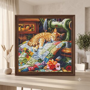 Könnte beinhalten: Ein gerahmtes Kreuzstichbild, das eine orangefarbene getigerte Katze zeigt, die auf einem bunten Patchwork-Quilt schläft. Die Szene umfasst eine grüne Vintage-Nähmaschine, einen Holzschrank, eine Garnrolle und leuchtende Blumen im Vordergrund.
