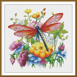Puede incluir: Un patrón de bordado en punto de cruz que presenta una libélula grande con alas de color naranja y rojo vibrante y un cuerpo azul y amarillo, situada sobre un grupo de flores coloridas que incluyen flores amarillas, rosas y azules con hojas verdes.