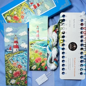 Könnte beinhalten: Ein Kreuzstich-Set mit einer Küstenszene mit Leuchtturm, Segelbooten und Blumen. Das Set enthält eine Stickleinwand, Stickgarn und eine Farbkarte. Die Farbpalette umfasst Rot, Weiß, Blau und Grün.