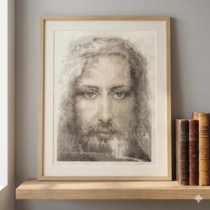 May include: Framed portrait of a man with long hair and a beard, rendered in a cross-stitch style. The artwork is in a light wood frame and rests on a wooden shelf. Several antique books are visible to the right of the frame.