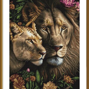 Puede incluir: Un primer plano de un león y una leona con sus cabezas juntas, rodeados de exuberante vegetación verde y flores coloridas. El león tiene una melena marrón oscura y la leona tiene un pelaje marrón claro. El fondo es un bosque oscuro y borroso.