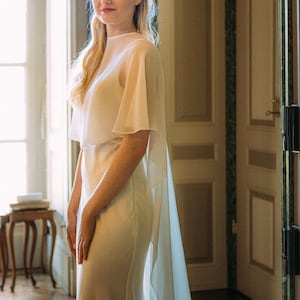 a modern bride wears sheer bridal cape made of light sheer chiffon