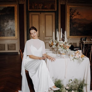 a modern bride wears sheer bridal cape made of light sheer chiffon