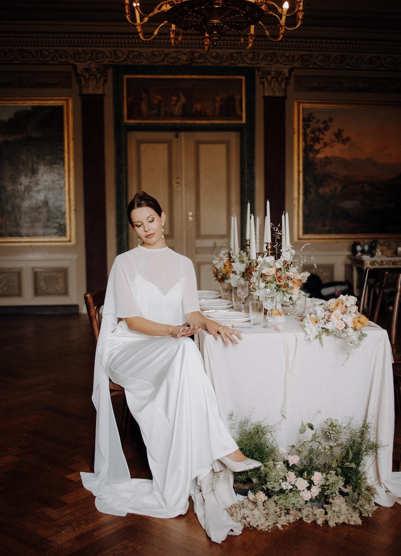 a modern bride wears sheer bridal cape made of light sheer chiffon