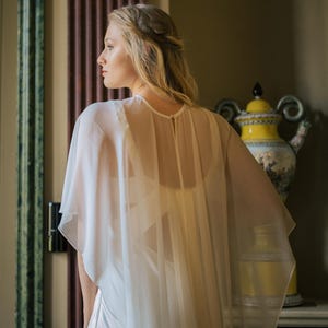 a modern bride wears sheer bridal cape made of light sheer chiffon