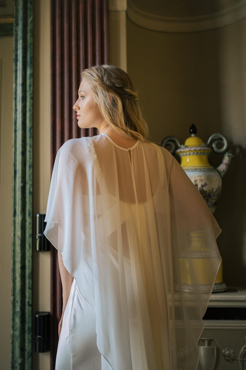 a modern bride wears sheer bridal cape made of light sheer chiffon