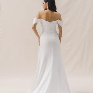 May include: A white off-the-shoulder wedding dress with a fitted bodice and a flowing skirt.
