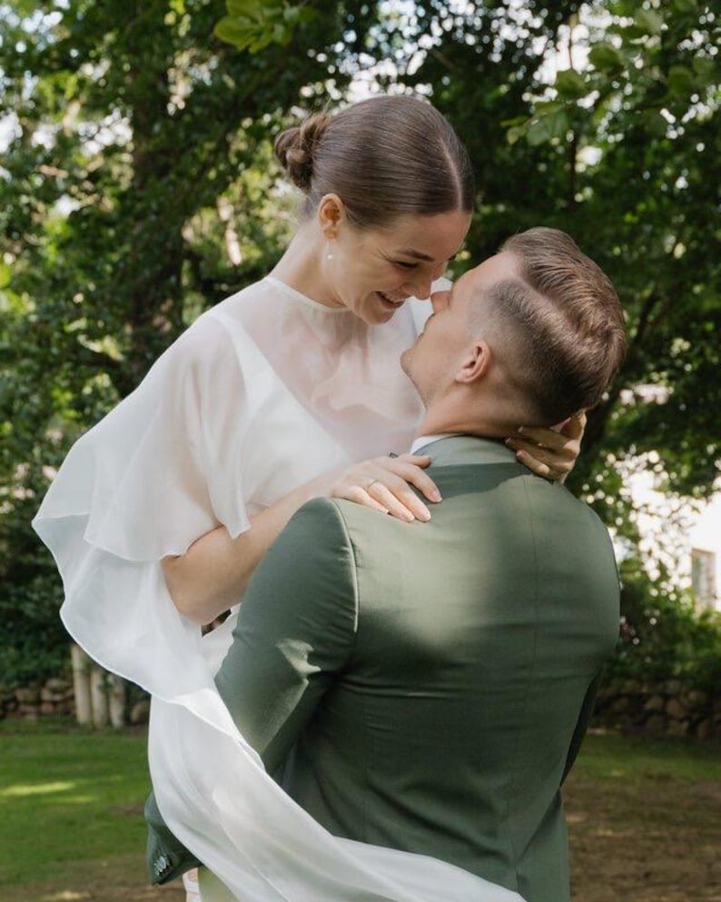 a modern bride wears sheer bridal cape made of light sheer chiffon