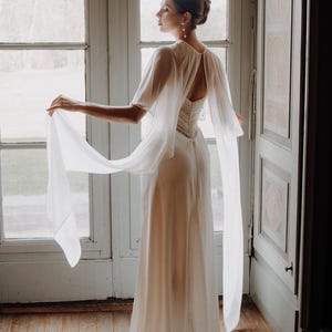 a modern bride wears sheer bridal cape made of light sheer chiffon